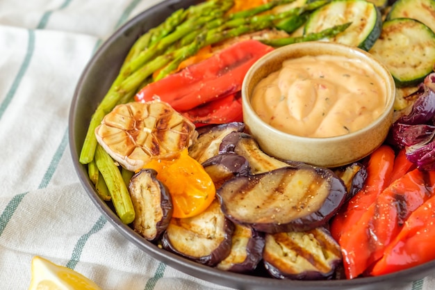 Verduras asadas en un plato con salsa, enfoque selectivo.