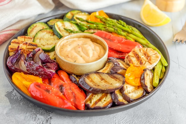 Verduras asadas en un plato con salsa, enfoque selectivo.