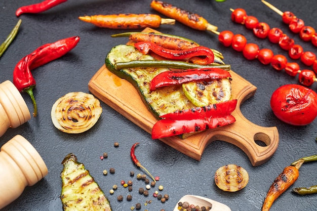 Foto verduras asadas en una tabla de madera en la vista lateral de la mesa negra