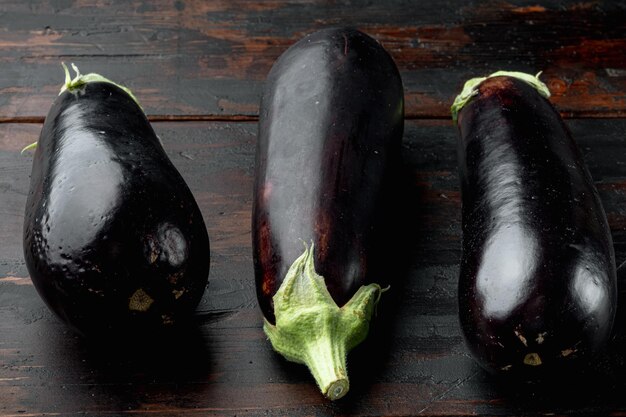 Verduras de berenjena de berenjena moradas reflectantes vibrantes sobre fondo de mesa de madera oscura antigua