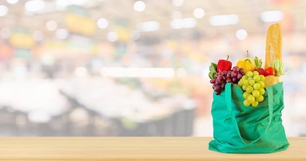 Verduras en bolsa de compras en la mesa de madera con fondo desenfocado de la tienda de comestibles del supermercado