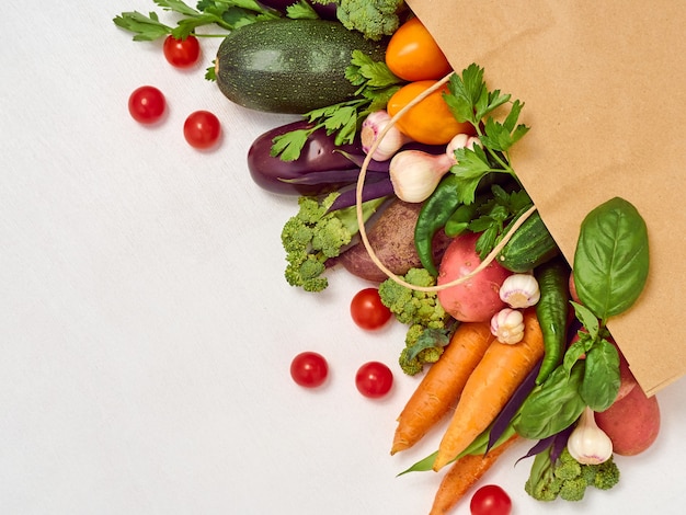 Verduras en bolsa de papel sobre fondo blanco.