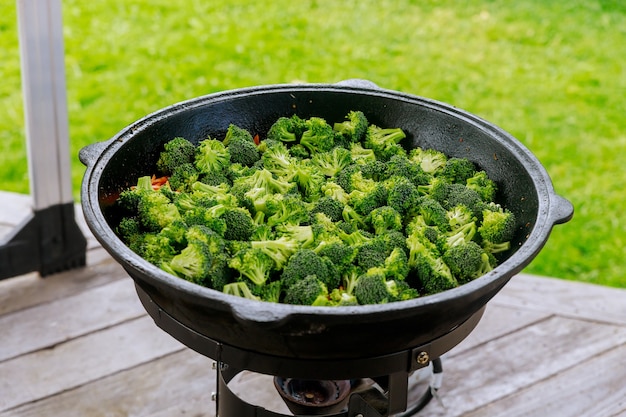 Verduras y brócoli cocinar en caldero en llamas al aire libre