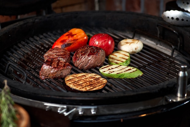 Verduras y carne chisporroteando a la parrilla con llamas, cerrar