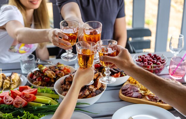 Las verduras y la carne se comen a la parrilla en la mesa con vino y gente.