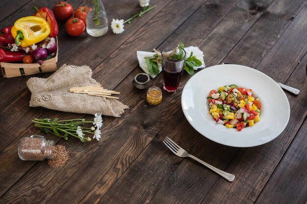 Verduras coloridas frescas en una placa blanca en un fondo de madera oscuro