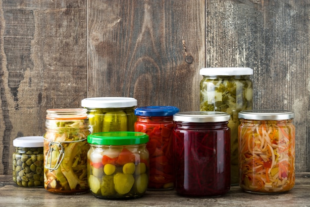 Verduras conservadas fermentadas en frasco sobre mesa de madera.