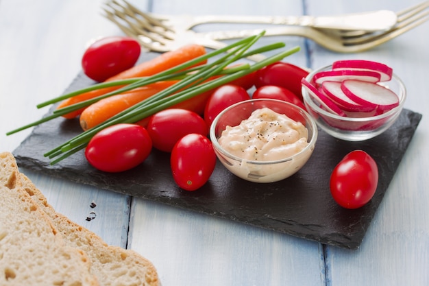 Verduras crudas frescas con salsa en pizarra