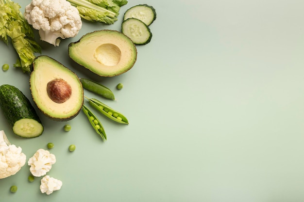 Verduras crudas frescas y verduras sobre un fondo claro cebolla verde lechuga calabacín pepino guisantes eneldo perejil menta coliflor con espacio para texto plano vista superior