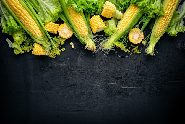 Verduras crudas de maíz sobre un fondo de madera negra Vista superior Espacio libre para el texto