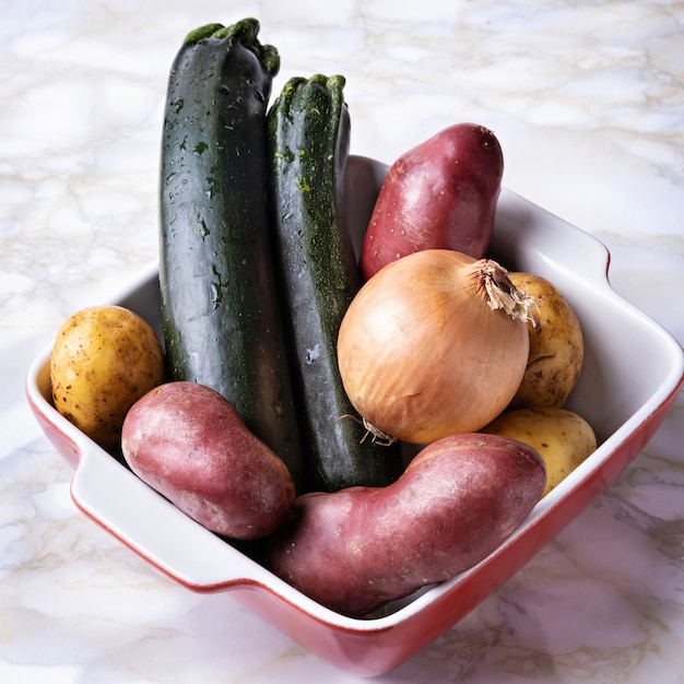 Verduras crudas presentadas en cazuela de barro antes de su preparación