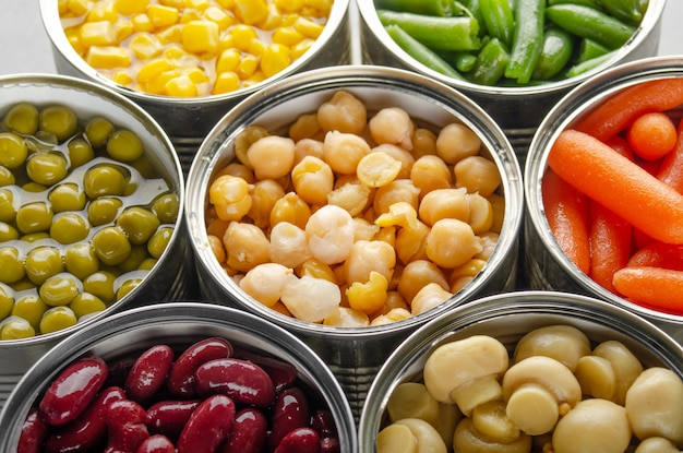 Verduras enlatadas en latas abiertas en la mesa de la cocina Fondo de alimentos no perecederos de larga duración