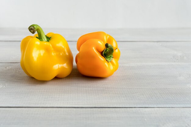 Verduras enteras pimientos amarillos forma fea en el fondo blanco de madera con espacio de copia