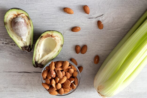 Verduras frescas: aguacate, apio, almendras, en mesa. Vista superior.