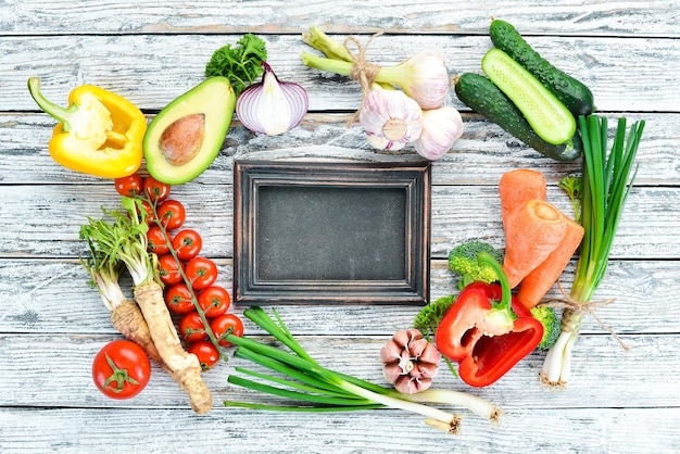 Verduras frescas Aguacate pepino cebolla ajo tomates zanahorias rábano picante Vista superior Espacio libre para el texto