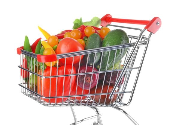 Verduras frescas en carrito de compras sobre fondo blanco.