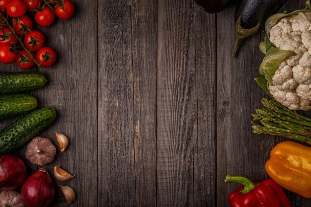 Foto verduras frescas para cocinar sobre fondo de madera oscura.