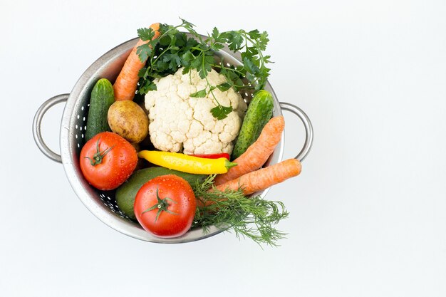 Verduras frescas en un colador sobre una mesa blanca