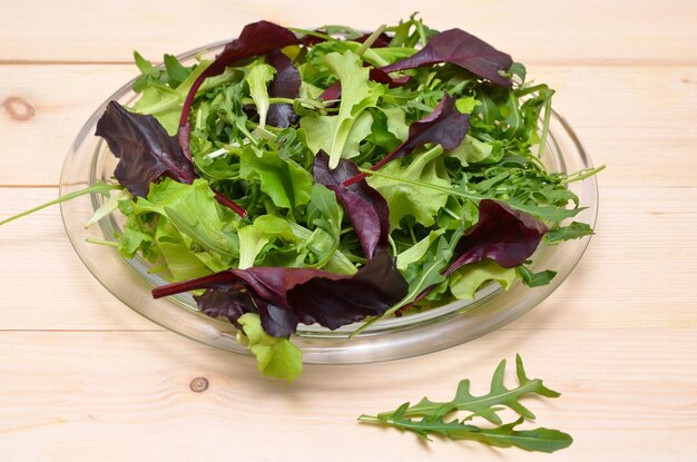 Verduras frescas em um prato de alface e rúcula em um fundo claro