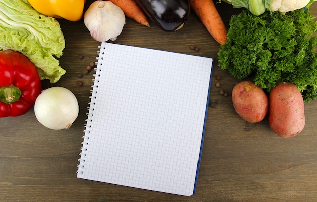 Verduras frescas y especias y papel para notas, en madera