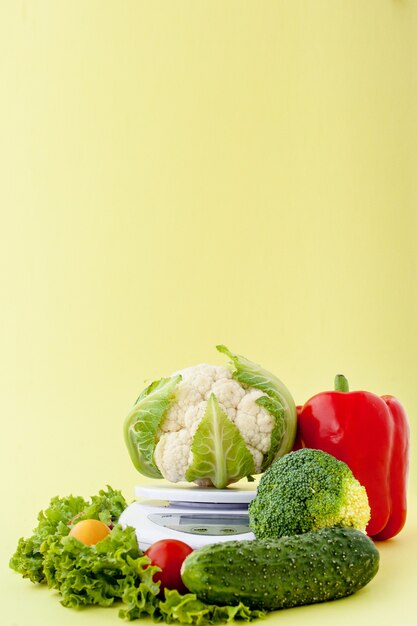 Verduras frescas en florero sobre fondo amarillo. Alimentación saludable, planificación de la dieta, pérdida de peso, desintoxicación, concepto de agricultura orgánica.