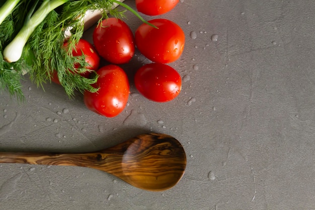 Verduras frescas y fragantes y una cuchara de bambú se encuentran en la cocina gris