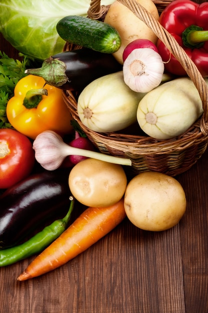 Verduras frescas maduras en una canasta sobre mesa de madera