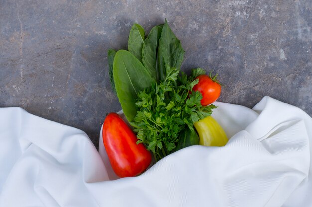 Foto verduras frescas en una piedra con un paño blanco