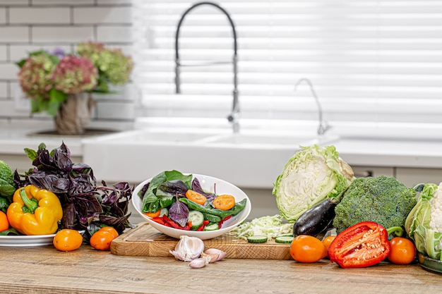 Foto verduras frescas en el proceso de preparación de ensalada en una mesa de madera.