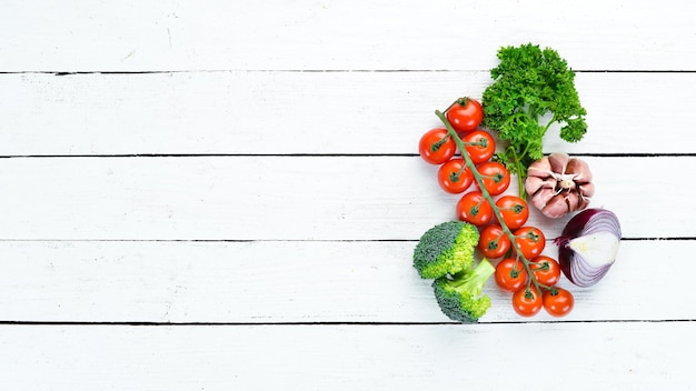 Verduras frescas sobre un fondo blanco de madera. Aguacates, tomates, ajo, perejil, paprika. Vista superior. Espacio libre para su texto.