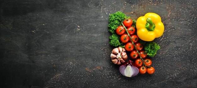 Verduras frescas sobre un fondo negro Aguacates tomates ajo perejil pimentón Vista superior Espacio libre para su texto