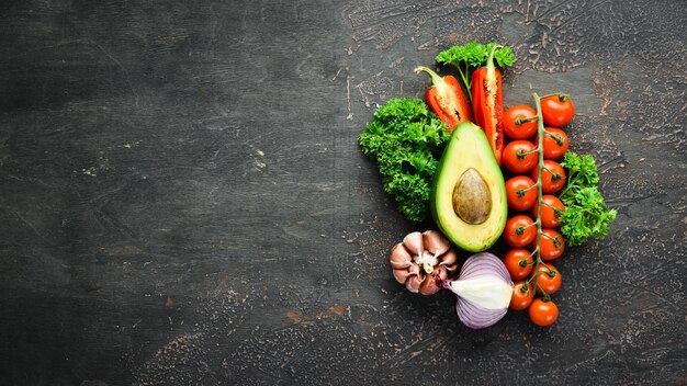 Verduras frescas sobre un fondo negro Aguacates tomates papas pimentón cítricos Vista superior Espacio libre para su texto