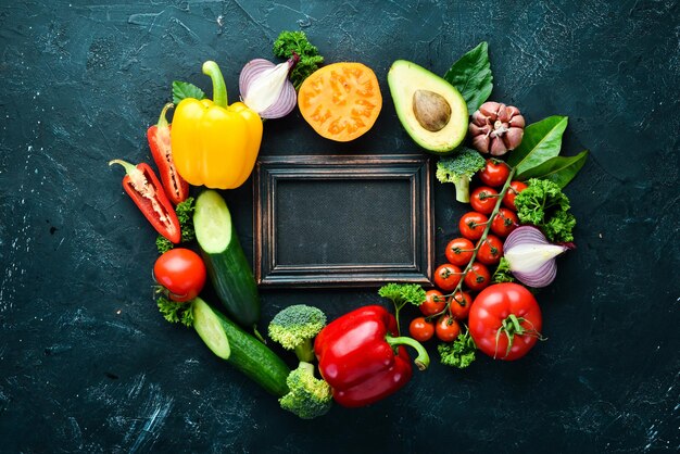 Verduras frescas sobre un fondo negro. Aguacates, tomates, patatas, pimentón, cítricos. Vista superior. Espacio libre para su texto.