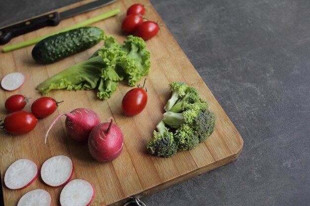 Verduras frescas en una tabla de cortar sobre una mesa gris