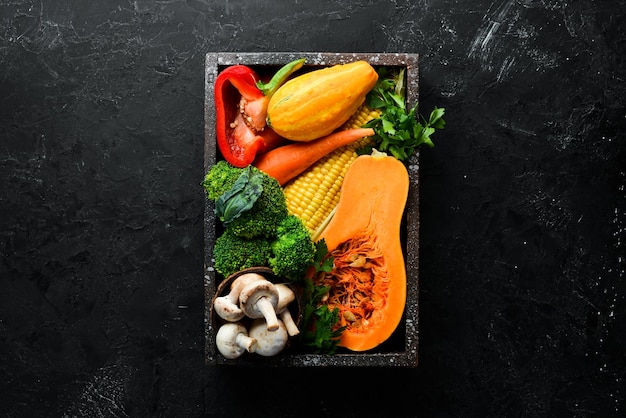 Verduras frescas de temporada sobre un fondo de piedra negra Calabaza tomate aguacate pepino cebolla zanahoria Comida de otoño Vista superior Espacio de copia libre