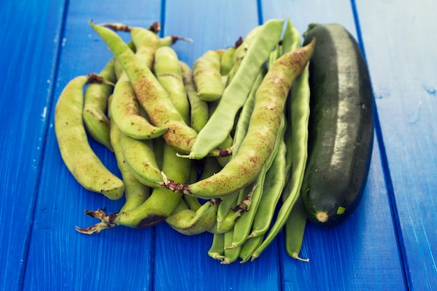 Verduras frescas verdes sobre superficie de madera azul