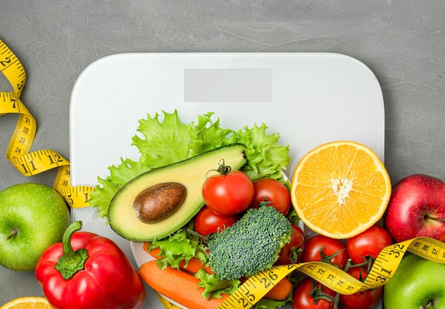 verduras y frutas en balanzas sobre un fondo de hormigón gris concepto de alimentación saludable y pérdida de peso