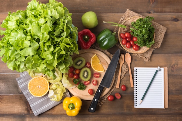 verduras y frutas con cuaderno sobre fondo de madera