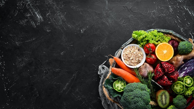 Verduras y frutas frescas en una caja de madera sobre un fondo negro Alimentos orgánicos Vista superior Espacio de copia libre