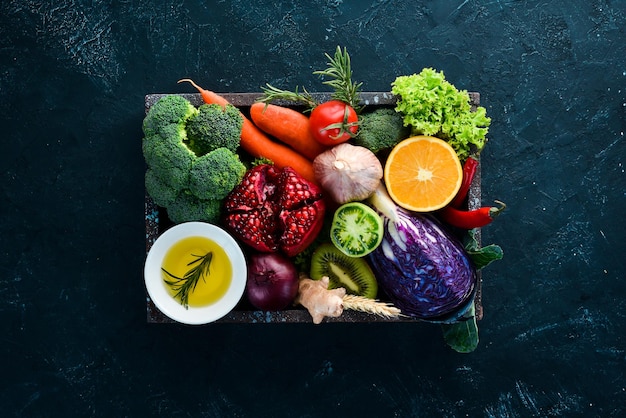 Verduras y frutas frescas en una caja de madera sobre un fondo negro Alimentos orgánicos Vista superior Espacio de copia libre