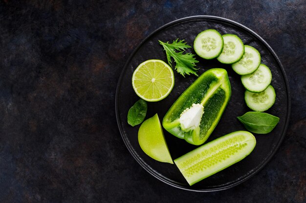 Verduras y frutas sobre un fondo oscuro. Comida de dieta verde en un plato negro. Comida sana. Vista superior. Copia espacio