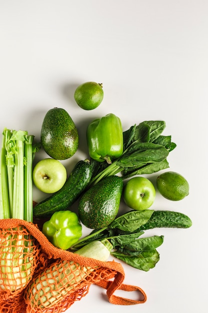 Verduras y frutas verdes en bolsa de hilo naranja