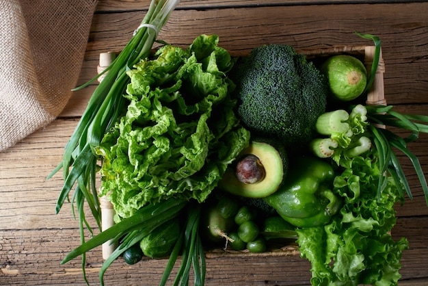 Verduras y frutas verdes y verduras en una cesta de mimbre marrón sobre un fondo de madera. Concepto de alimentación saludable