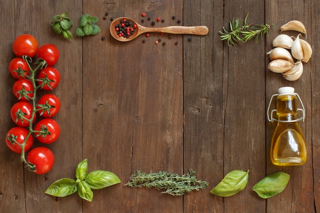 Verduras, hierbas y aceite de oliva en vista superior de la mesa de madera