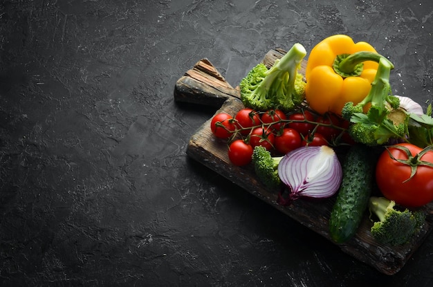 Verduras maduras Verduras frescas sobre fondo de piedra negra Frutas tropicales Vista superior Espacio libre para el texto