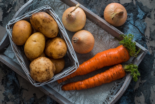 Foto verduras mixtas. patatas, zanahorias y cebollas en una cesta. cocinar comida vegetariana