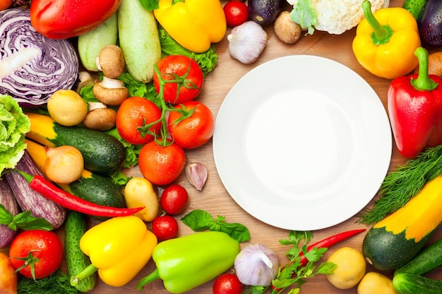 Verduras orgánicas frescas alrededor de un plato blanco