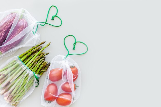 Verduras orgánicas frescas en bolsas de compras de productos ecológicos reutilizables endecha plana, vista superior