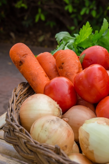 Verduras orgánicas frescas en cesta de mimbre en el fondo de madera