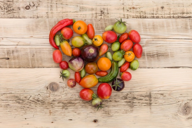 Verduras orgánicas tomates y pimentón en forma de corazón sobre fondo de madera vintage